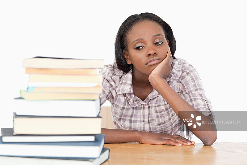 看着一堆书的无聊学生图片素材