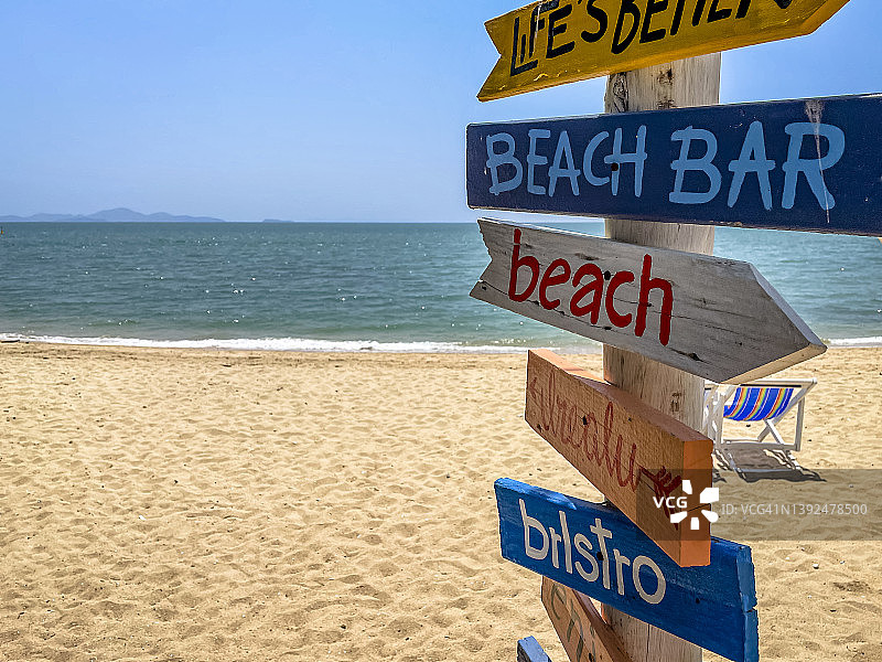 带有海滩、小酒馆、酒吧和放松等情绪箭头的彩色泰国海滩标志。沙滩上有趣的标志牌，地平线上有海滩和海景。家庭假日、海滩和度假营销的概念作品图片素材