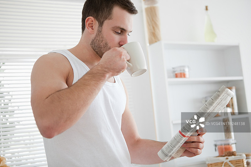 年轻男人边喝咖啡边看新闻图片素材