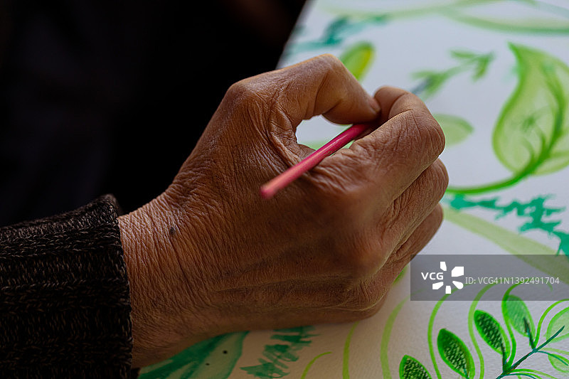 拿着画笔的布满皱纹的老年人的手图片素材