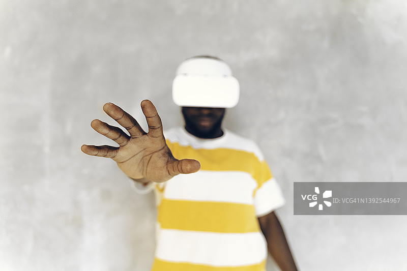 在虚拟现实眼镜中向镜头伸手的非洲裔男子图片素材