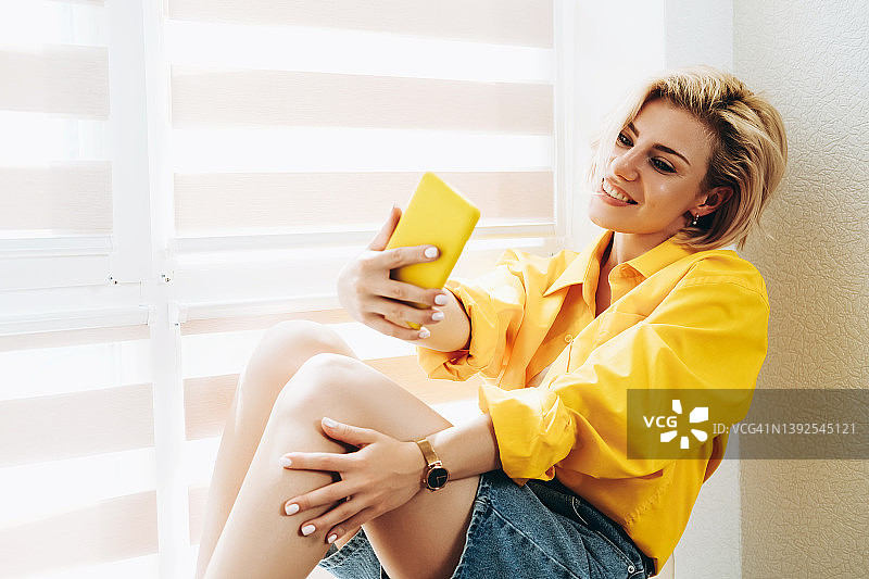 坐在窗台自拍的年轻女子图片素材