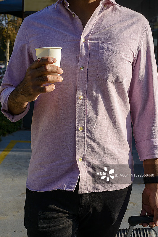 携带手提行李和咖啡杯的年轻男子图片素材
