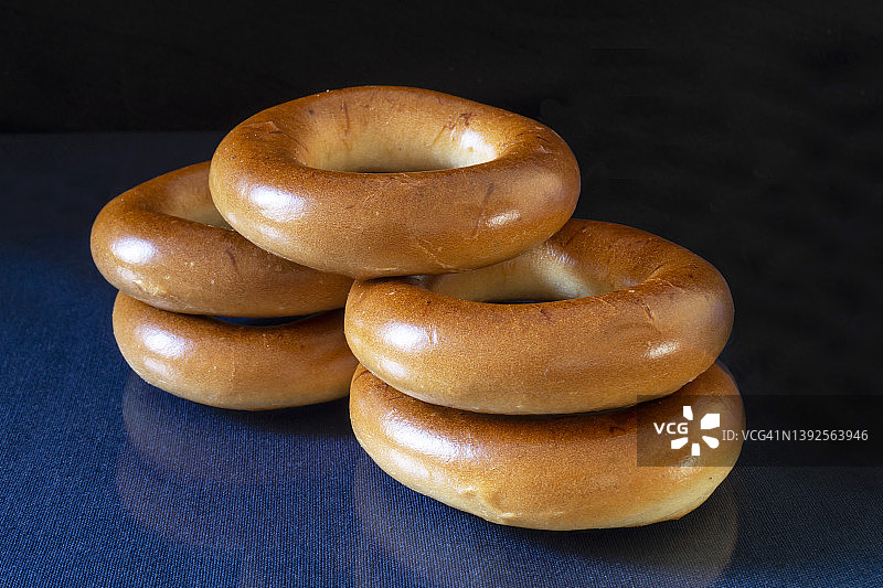 蓝色桌子上带有倒影的圆形百吉饼图片素材