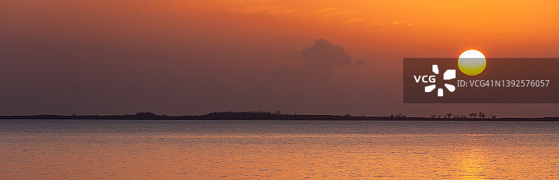 日落时分的橙色天空下的海洋全景图片素材