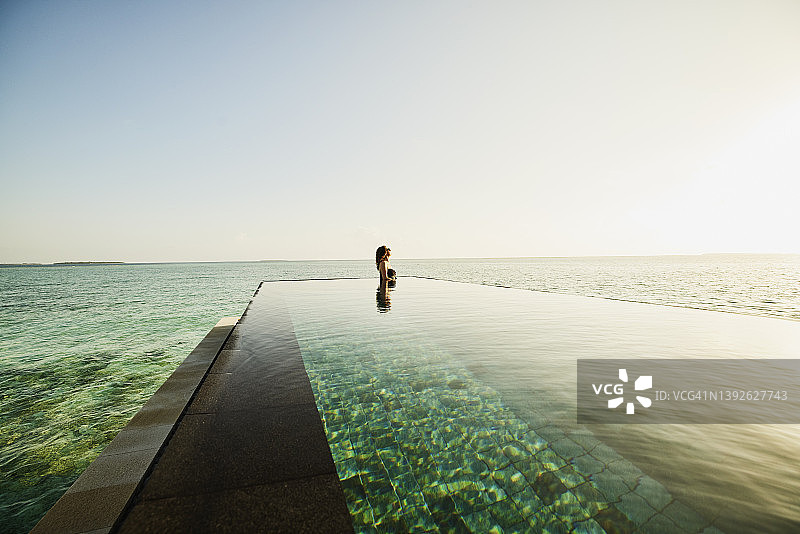 成熟女性在海边无边泳池放松身心的超广角镜头图片素材