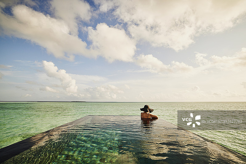 在无边泳池中放松的成熟女人的超广角镜头图片素材