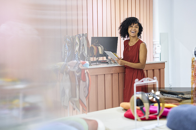 拉美帽子店主站在柜台旁，使用平板电脑图片素材