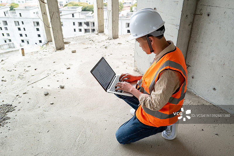 中年工人在建筑工地使用笔记本电脑图片素材