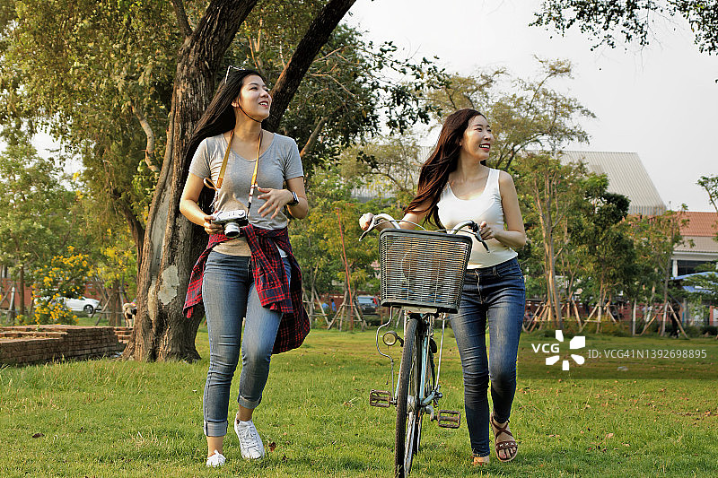 在公园骑自行车的女子，两个女性朋友在度假图片素材