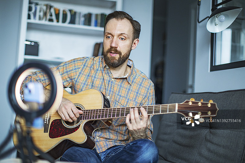 年轻男人在家线上教弹吉他图片素材
