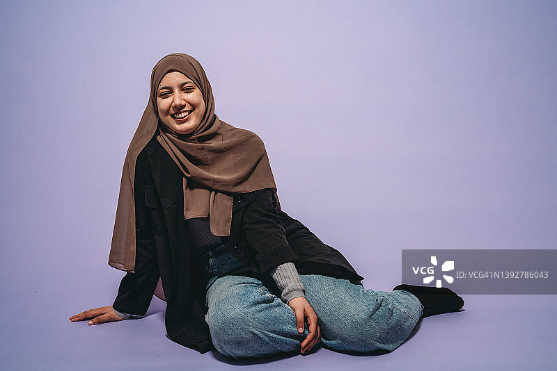 年轻女子坐在紫色背景前的肖像图片素材