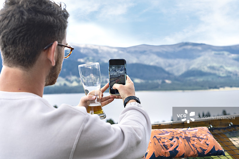 年轻的拉丁裔游客在旅行和探索内乌萨水库时，在度假期间用智能手机在自然环境中自拍。图片素材