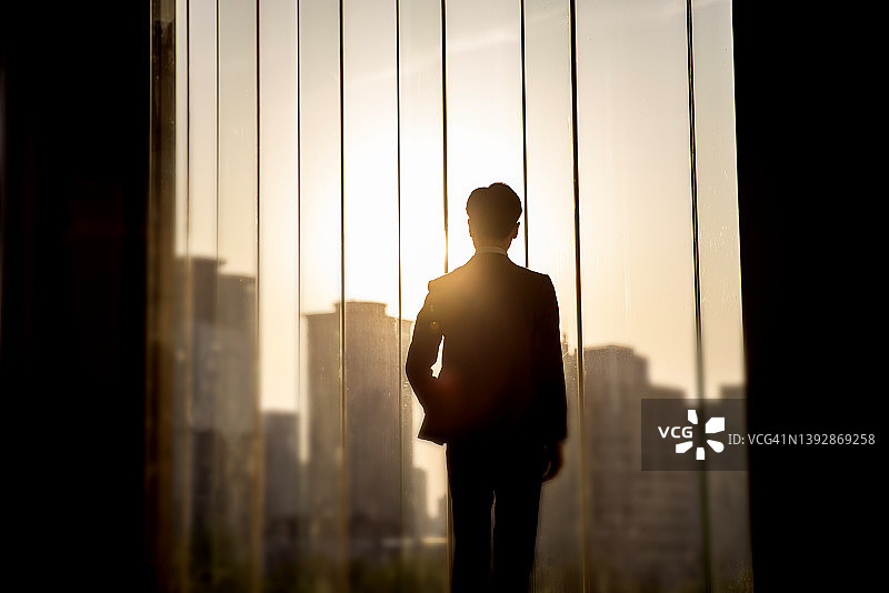 从办公室的大窗户向外看的商人图片素材