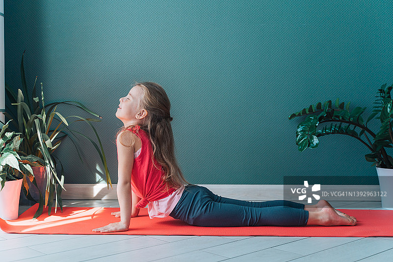 可爱的小金发女孩在运动课上做瑜伽图片素材