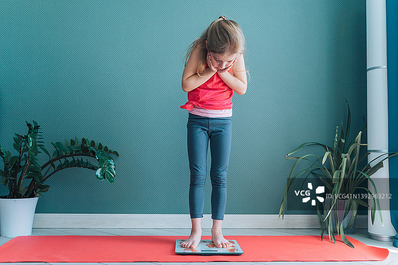 站在体重秤上的可爱赤脚女孩图片素材