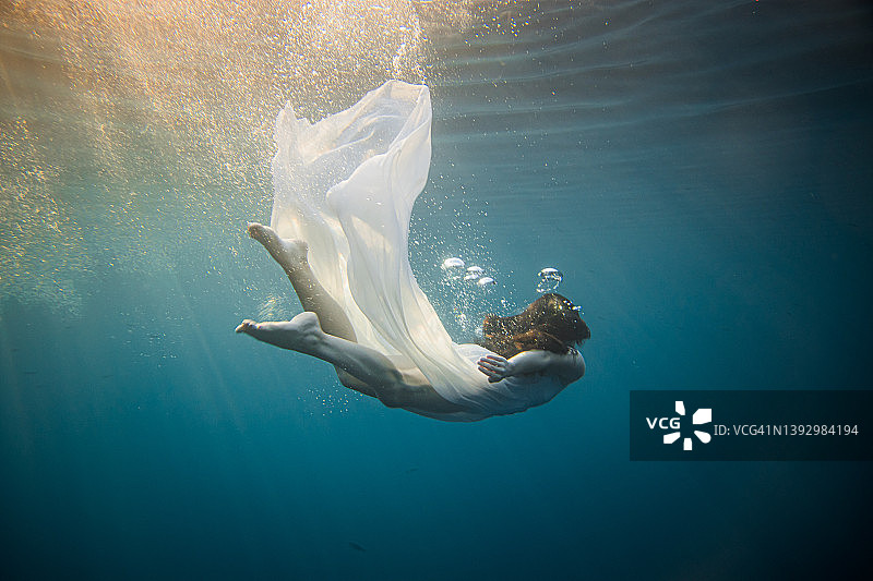 棕色头发、身穿白色连衣裙的女人在海中潜水（侧视）图片素材