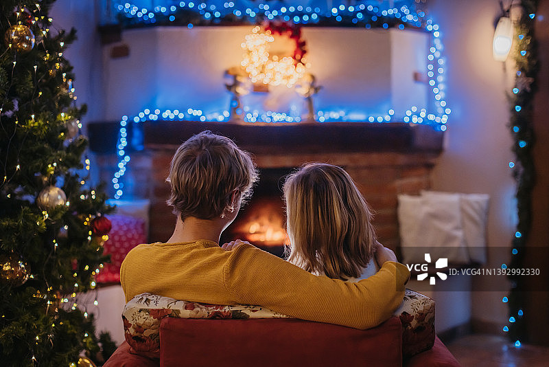 情侣在家中圣诞树旁的扶手椅上并肩而坐图片素材