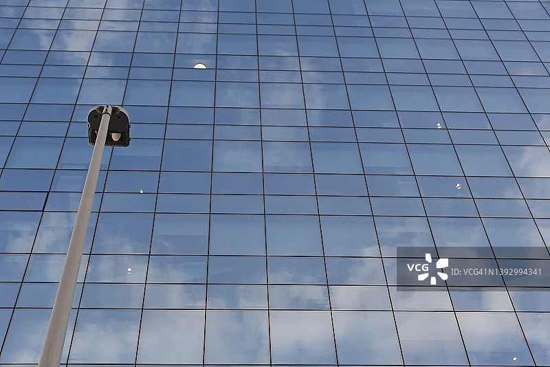 有云层反射的玻璃幕墙建筑的仰视角度照片图片素材