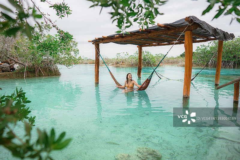 女人在墨西哥巴卡拉尔泻湖的水上吊床上休息图片素材