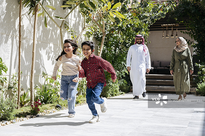 充满活力的中东儿童在户外家庭住宅赛跑图片素材