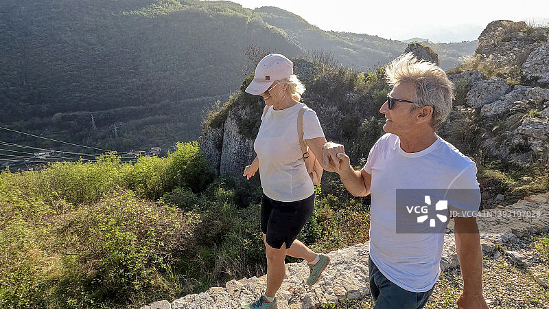 年长夫妇手牵手走在石壁上图片素材