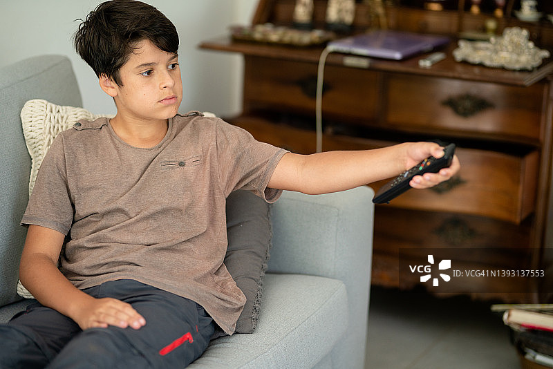 男孩用遥控器换电视频道图片素材