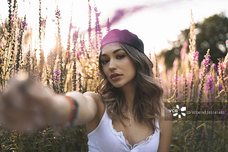 粉色鲜花前的漂亮棕发年轻女人图片素材