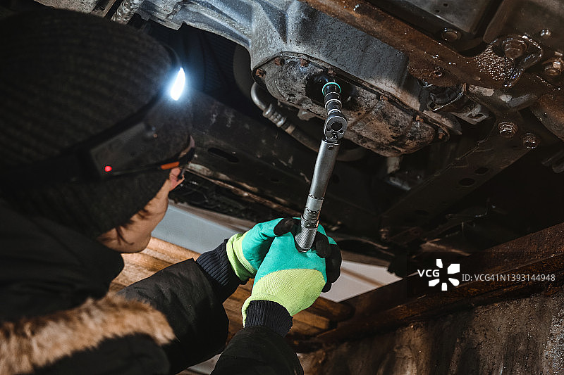 汽车修理工使用汽车扳手更换油底壳图片素材