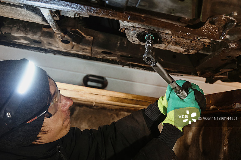 汽车修理工使用汽车扳手更换油底壳图片素材