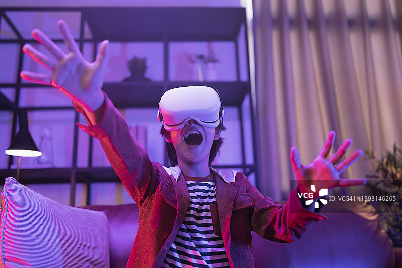亚洲儿童戴VR眼镜在家玩游戏图片素材