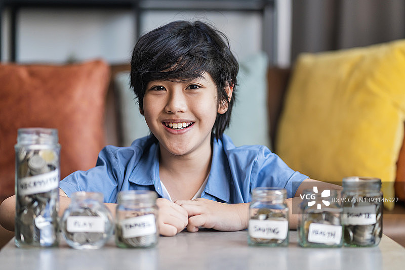 亚洲儿童将硬币存入储蓄罐，家庭理财教育图片素材