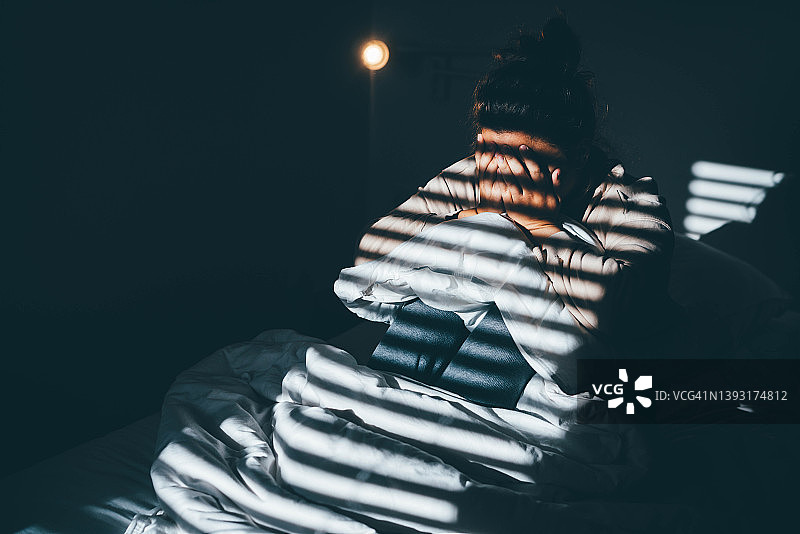 悲伤沮丧的年轻女人坐在家里的床上图片素材