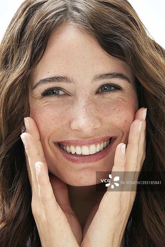 年轻黑发女子面部特写，手 touching 面颊图片素材