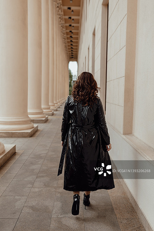 穿着黑色风衣和短款连衣裙的丰满深色头发的年轻欧洲女人图片素材
