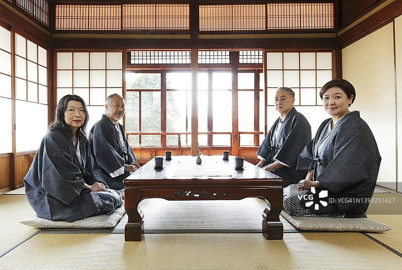 两对穿着日式浴衣的情侣坐在日式旅馆房间里看着镜头图片素材