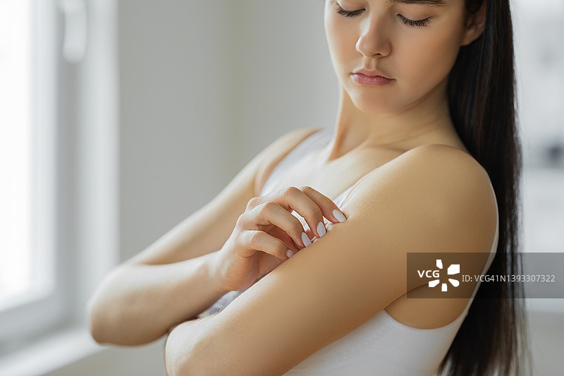 年轻女人挠手臂图片素材