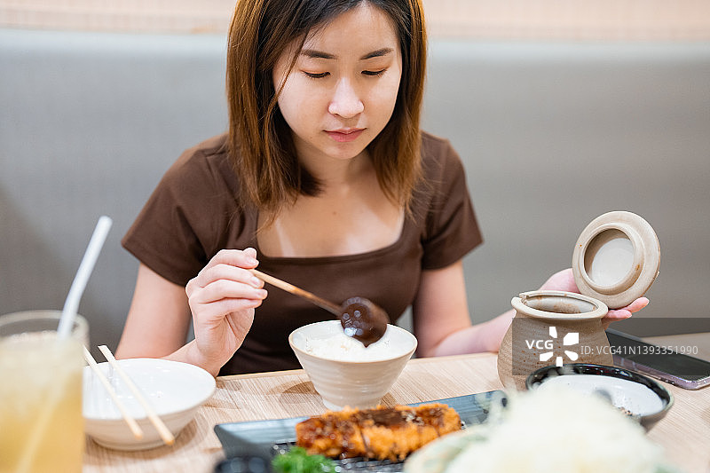 年轻女人在餐厅的炸猪排上涂酱汁图片素材