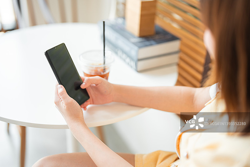 年轻亚洲女子在咖啡馆放松时发短信图片素材