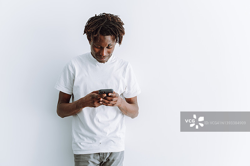 在白色演播室背景下手持智能手机向下看的年轻商人，留有复制空间图片素材