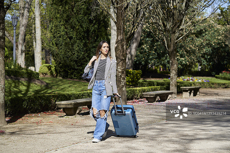穿着牛仔裤、拖着行李箱抵达欧洲开始学习的女大学生图片素材