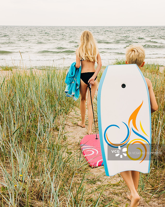 两个孩子带着冲浪板走向海滩图片素材