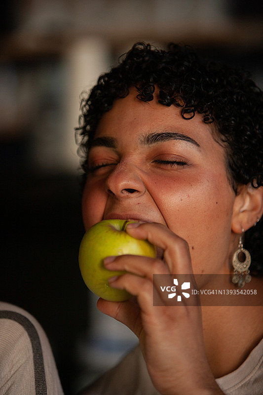 短发年轻女子咬苹果的竖版肖像图片素材