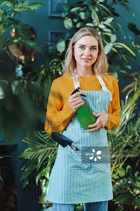 花卉温室店的金发女店主拿着喷雾器图片素材