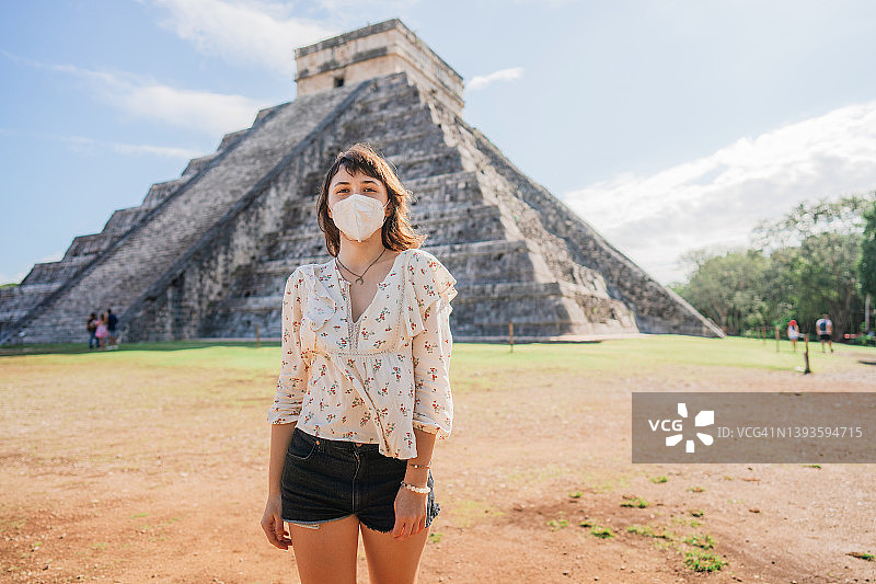 戴着面具的女人，背景是墨西哥奇琴伊察金字塔图片素材
