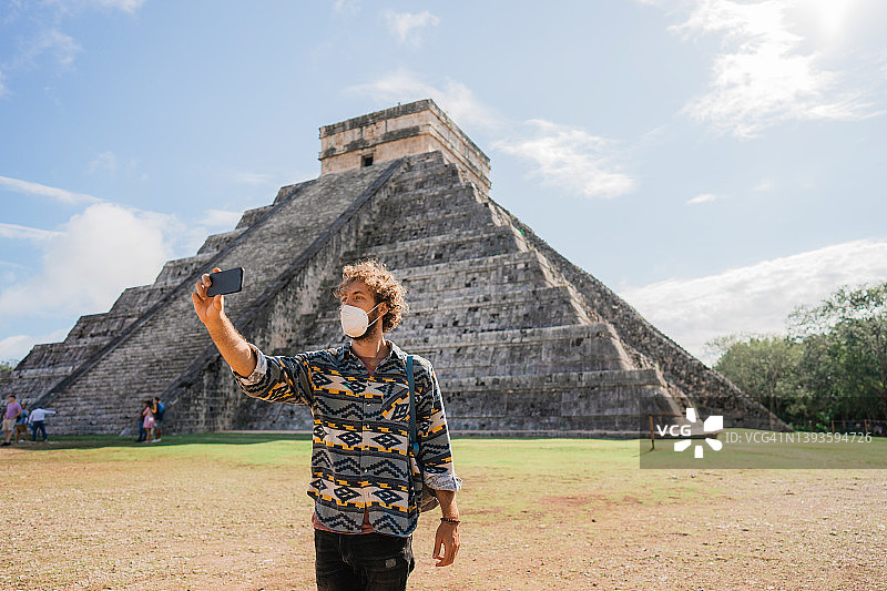 戴着面具的男人在墨西哥奇琴伊察金字塔背景下自拍图片素材