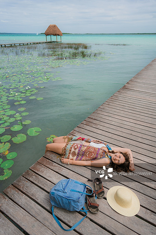 女人躺在巴卡拉尔泻湖的码头上图片素材