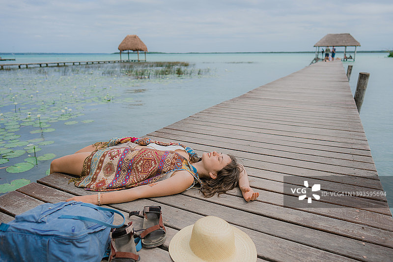 女人躺在巴卡拉尔泻湖的码头上图片素材