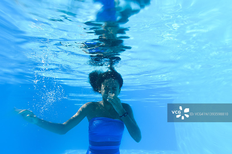 一个黑皮肤女孩潜入水下游泳池。儿童的积极有趣的消遣。夏天。暑假。假期图片素材
