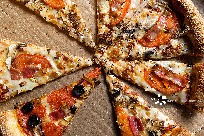 美味的意大利披萨：外卖披萨盒装，白色背景。番茄、意大利辣香肠、培根和奶酪披萨切片，不健康的生活方式快餐理念。图片素材